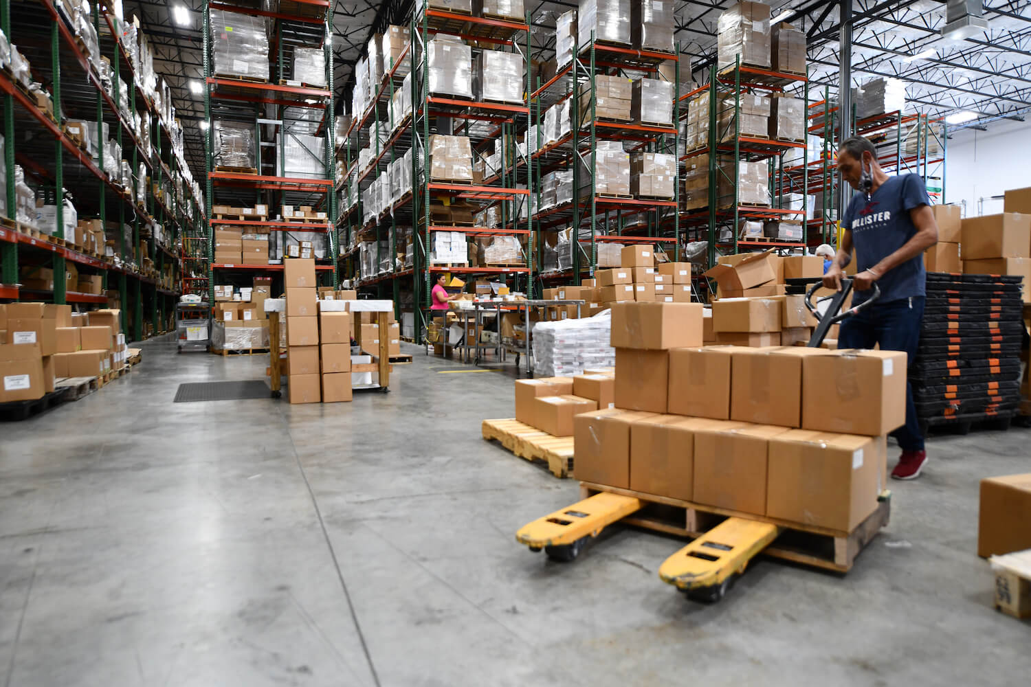 Employee operating pallet jack in warehouse