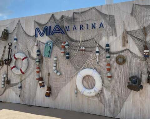 Outdoor wall at a beach with MIA Marina items hanging from it