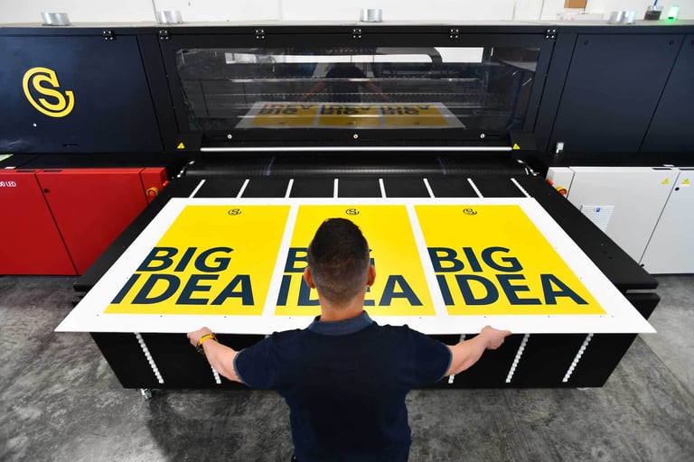 Employee removing banner from large-scale printer