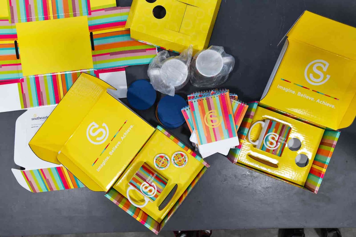 Gift boxes with rainbow printed items, including mugs and notebooks with the Southeastern logo