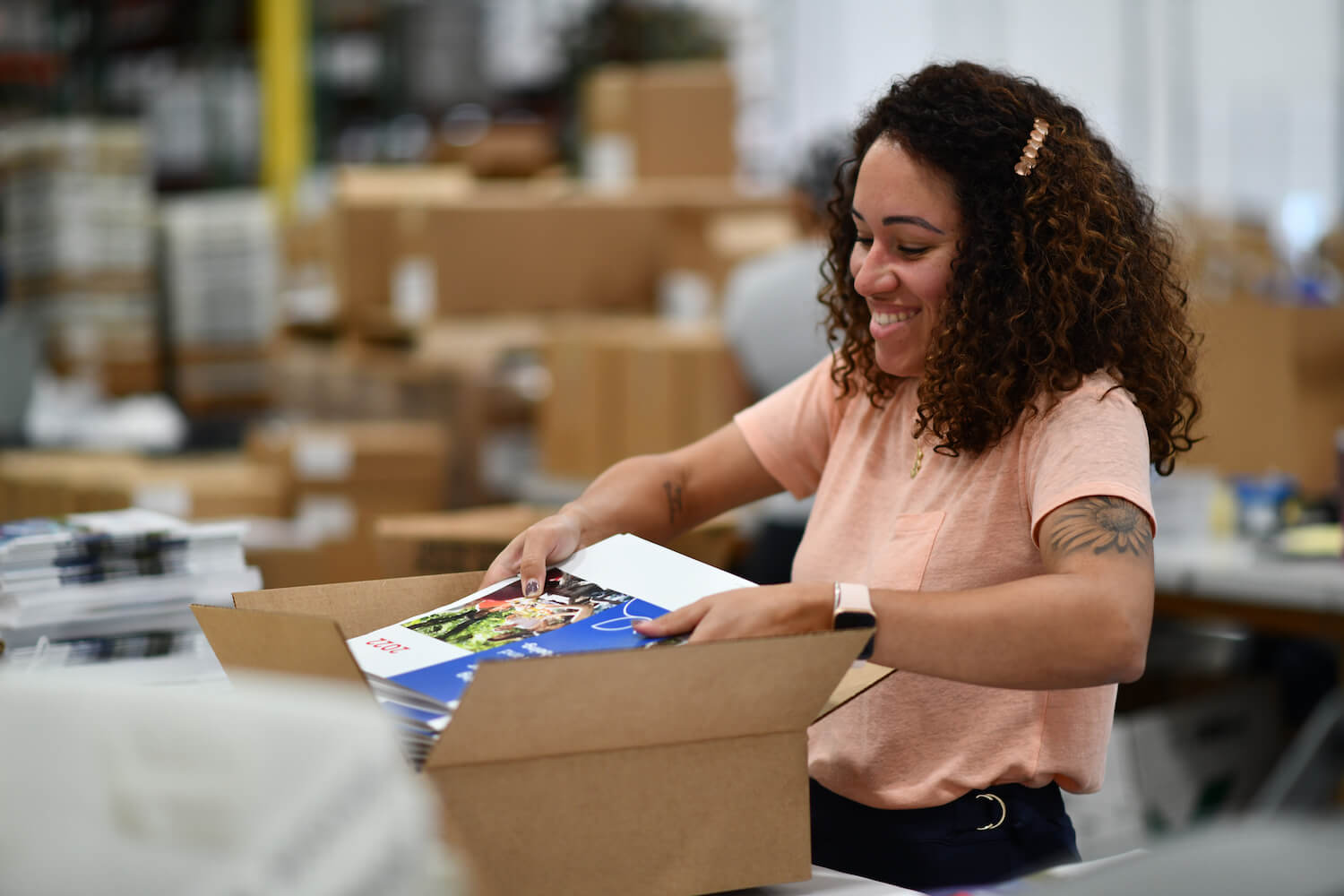 Woman placing brochures in shipping boxes-1